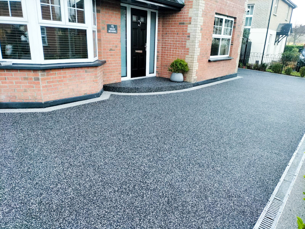 A photo of a dark grey resin driveway in Southampton with a grey block paved edge